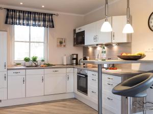 a kitchen with white cabinets and a counter top at Ferienhaus Schilfrohrsaenger 28 in Fuhlendorf