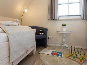 a bedroom with a bed and a chair and a table at Ferienhaus Schilfrohrsaenger 28 in Fuhlendorf