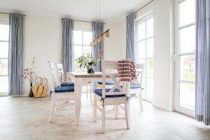 a white dining room with a table and chairs at Ferienhaus Schilfrohrsaenger 31 in Fuhlendorf