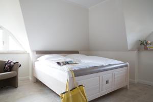 a white bed in a bedroom with a yellow bag at Ferienhaus Seeadler 24 in Fuhlendorf