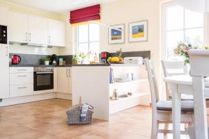 a kitchen with white cabinets and a table and chairs at Ferienhaus Schilfrohrsaenger 48 in Fuhlendorf +28 photos