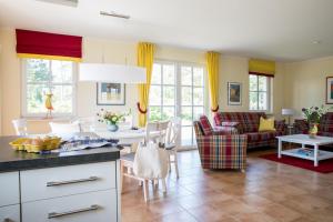 een keuken en een woonkamer met gele gordijnen bij Ferienhaus Schilfrohrsaenger 48 in Fuhlendorf