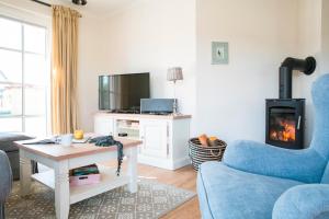 a living room with a blue couch and a fireplace at Ferienhaus Haubenlerche 59 in Fuhlendorf