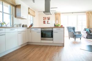 a kitchen with white cabinets and a living room at Ferienhaus Haubenlerche 59 in Fuhlendorf