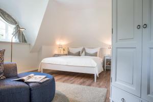 a bedroom with a white bed and a chair at Ferienhaus Haubenlerche 14 in Fuhlendorf