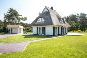 a house with a thatched roof on a lawn at Ferienhaus Haubenlerche 14 in Fuhlendorf