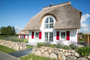 a cottage with a thatched roof and a stone wall at Ferienhaus Schilfrohrsaenger 61 in Fuhlendorf