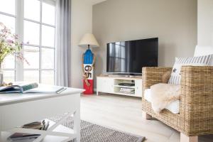 a living room with a television and a wicker chair at Ferienhaus Seeschwalbe 44 in Fuhlendorf
