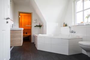 a white bathroom with a tub and a toilet at Ferienhaus Seeschwalbe 44 in Fuhlendorf +25 photos