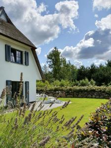 a white house with a yard and a stone wall at Ferienhaus Seeschwalbe 44 in Fuhlendorf