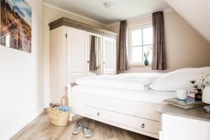 a bedroom with a white bed and a window at Ferienhaus Schilfrohrsaenger 30 in Fuhlendorf