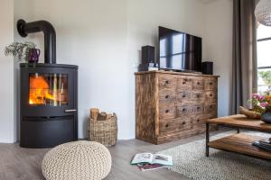 a living room with a fireplace and a television at Ferienhaus Haubenlerche 32 in Fuhlendorf