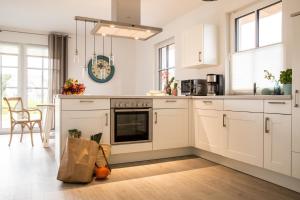 a kitchen with white cabinets and a table with a bag at Ferienhaus Haubenlerche 32 in Fuhlendorf