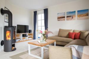 a living room with a fireplace and a couch at Ferienhaus Schilfrohrsaenger 8 in Fuhlendorf