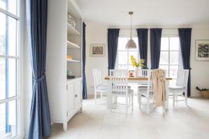 ein Esszimmer mit blauen Vorhängen sowie einem Tisch und Stühlen in der Unterkunft Ferienhaus Schilfrohrsänger 8 in Fuhlendorf