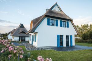 a house with a thatched roof and a garden at Ferienhaus Schilfrohrsaenger 8 in Fuhlendorf