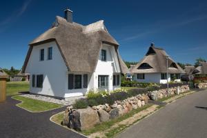 a white house with a thatched roof at Ferienhaus Seeschwalbe 33 in Fuhlendorf