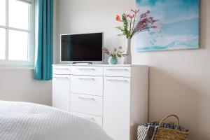 a bedroom with a white dresser with a tv on it at Ferienhaus Seeschwalbe 33 in Fuhlendorf