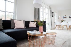 a living room with a black couch and a table at Ferienhaus Schilfrohrsaenger 45 in Fuhlendorf