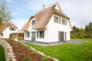 a white house with a thatched roof at Ferienhaus Schilfrohrsaenger 45 in Fuhlendorf