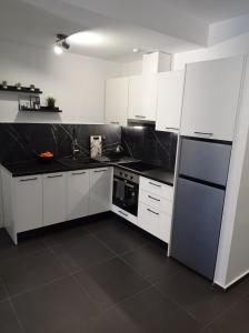 uma cozinha com armários brancos e bancadas pretas em NY Central 1 em Patra