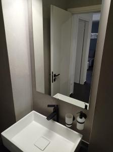 uma casa de banho com um lavatório branco e um espelho. em NY Central 1 em Patra
