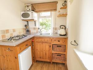 a kitchen with wooden cabinets and a sink and a window at The Mouse House in Blandford Forum