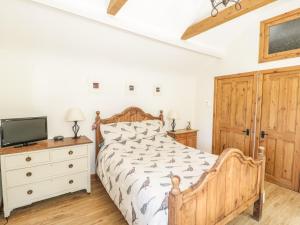a bedroom with a wooden bed and a tv at The Mouse House in Blandford Forum