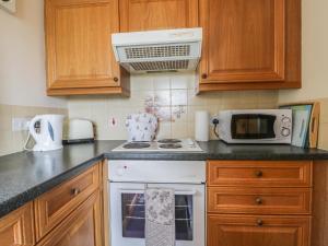 a kitchen with a stove and a microwave at Foxhunter Cottage in Whitby +7 photos