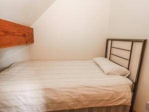 a small bedroom with a bed with white sheets at Foxhunter Cottage in Whitby