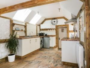 cocina con armarios blancos y techo abovedado en Barn Acre Cottage en Newquay