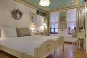 a bedroom with a large white bed and windows at ARCHONTARIKI Historic Boutique Hotel in Ioannina