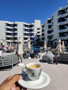 a person holding a cup of coffee on a patio at Luxury Apartment with pool view in Adeje