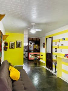een woonkamer met gele muren en een bank bij Condomínio Portais do Francês- Apto - PRAIA DO FRANCÊS/AL in Praia do Frances