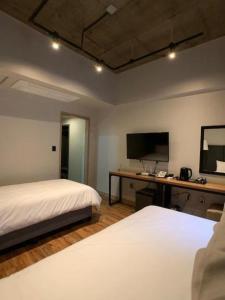 Jeju Renaissance Hotel في جيجو: غرفة نوم بسريرين ومكتب فيه تلفزيون