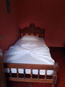 a bed with white sheets and a wooden headboard at Hospedaje la paloma in Moyogalpa