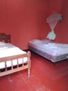 two beds in a room with a red wall at Hospedaje la paloma in Moyogalpa