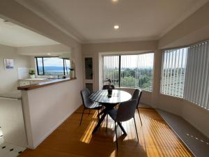 a dining room with a table and chairs and windows at Habour View - Tauranga Central in Tauranga