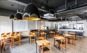 ein Restaurant mit Holztischen und -stühlen und einer Küche in der Unterkunft Jeju Renaissance Hotel in Jeju-do