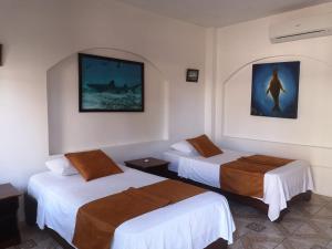 een hotelkamer met twee bedden en een foto aan de muur bij Hostal Sandrita in Puerto Villamil