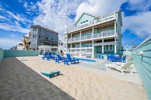 a building on the beach with blue chairs and a sandy beach at The Kinnakeeter 107 in Avon