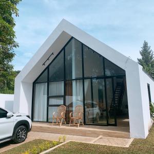 ein kleines Haus mit Glasfenstern und einem weißen Auto in der Unterkunft Casa de Gaudi Lembang in Lembang