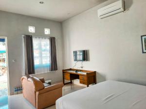 een slaapkamer met een bed, een bureau en een televisie bij Rosemary Homestay in Batu