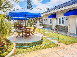 een patio met stoelen en een tafel met blauwe parasols bij Rosemary Homestay in Batu