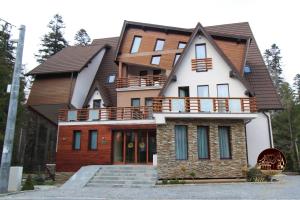 uma casa grande com uma varanda em cima em Oblique - Forest & Spa em Sinaia