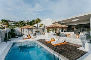 una piscina con sillas y sombrillas junto a un complejo en Concrete Retreat Villa, en Canggu