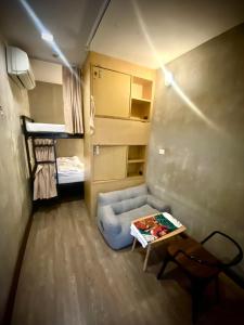 Habitación pequeña con sofá, mesa y cama en Cazz Hostel, en Bangkok