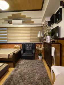 uma sala de estar com uma cama, um sofá e uma televisão em CedarPeak215 em Baguio