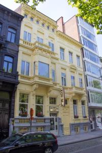 ein gelbes Gebäude mit einem davor geparkt in der Unterkunft Hotel Rubenshof in Antwerpen