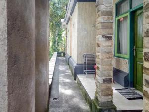 an alley between two buildings with a green door at DATON HOUSE near Bali Zoo Ubud Mitra RedDoorz in Darmasaba